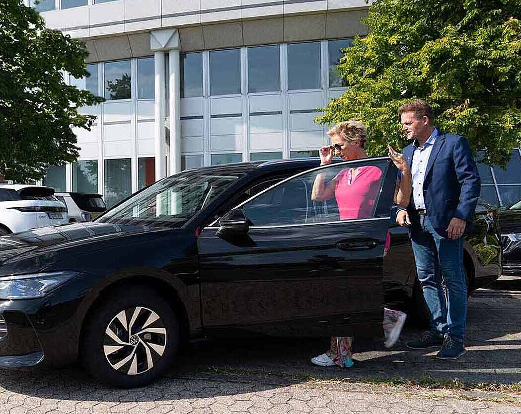 Dame steigt in ein Auto ein, Mitarbeiter der Autovermietung Arndt steht zur Seite | Auto mieten in Hannover