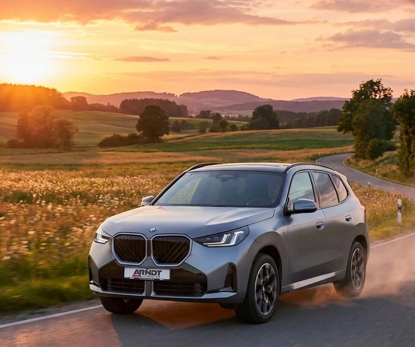 BMW X3 SUV auf Landstrasse vor Sonnenuntergang – BMW X3 mieten bei Arndt