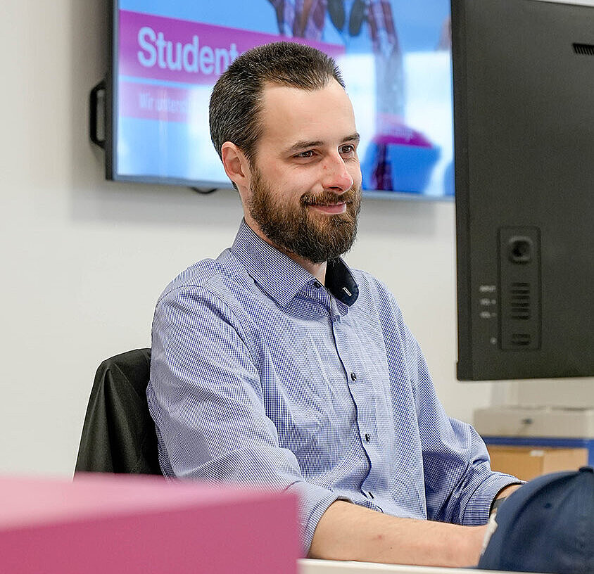 freundlicher Servicemitarbeiter sitzt am Computer in der Niederlassung der Autovermietung Arndt