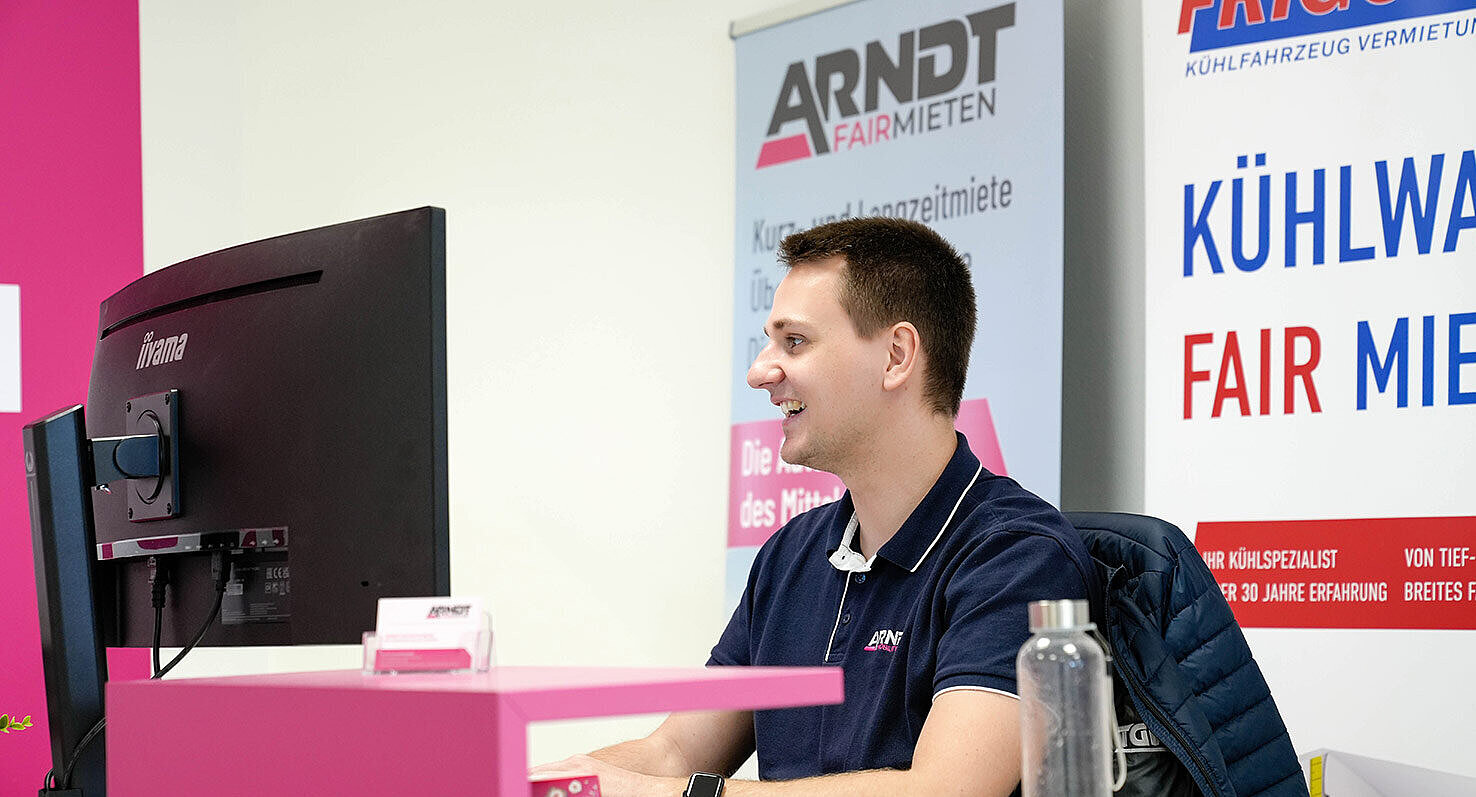 freundlicher Mitarbeiter der Autovermietung Arndt am Computer sitzend – Jetzt online Van buchen!