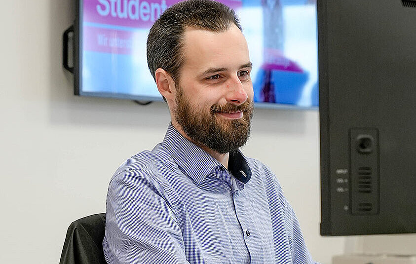 freundlicher Servicemitarbeiter sitzt am Computer in der Niederlassung der Autovermietung Arndt