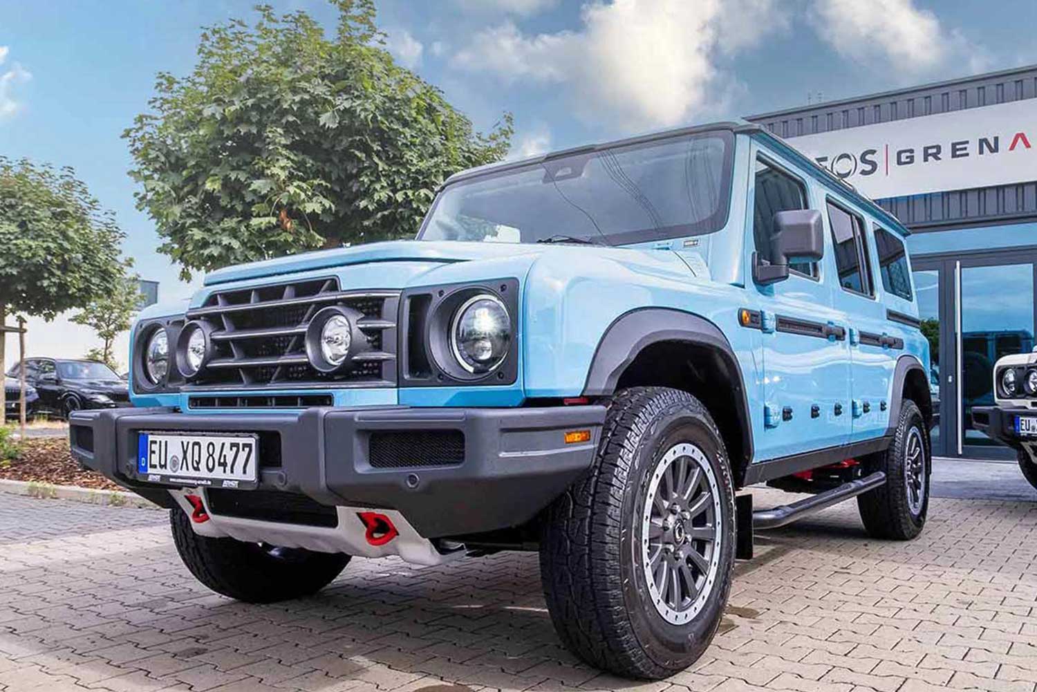 Blauer Ineos Grenadier vor einem Autohaus | Autovermietung Arndt
