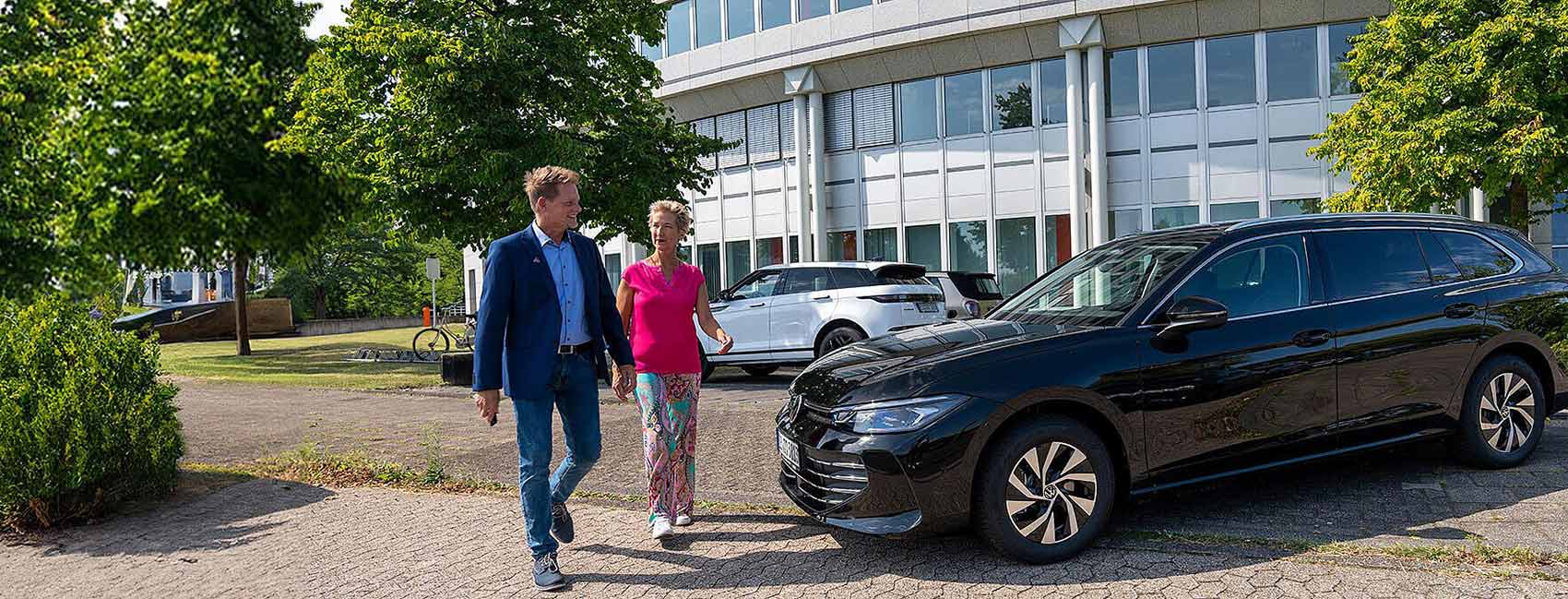 Mann und Frau vor einem Auto, das vor Bürogebäude steht | Autovermietung Arndt Hannover