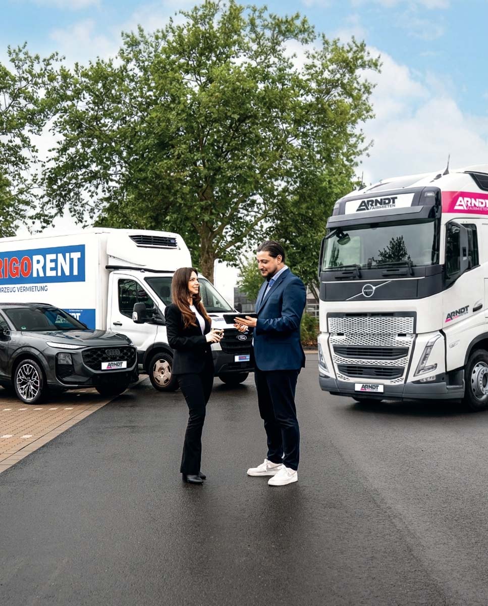 Mitarbeiter der Autovermietung Arndt besprechen Fahrzeugvermietung vor Transporter, PKW und LKW der Flotte